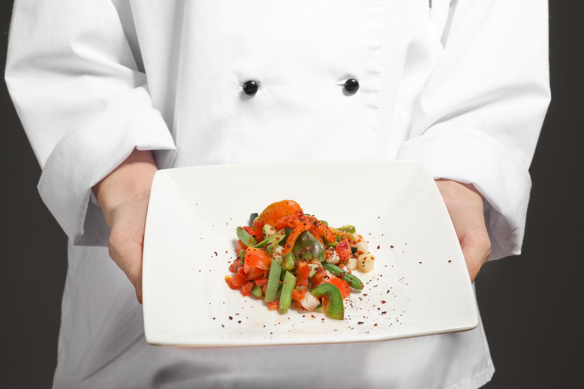 Chef mostrando un plato apetitoso en cocina moderna